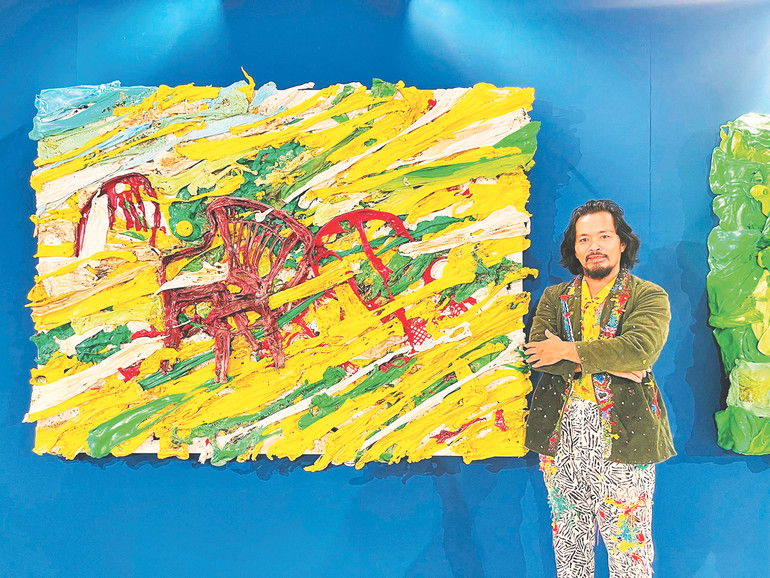 Họa sĩ Nguyễn Quốc Dân bên tác phẩm làm từ nhựa tái chế.