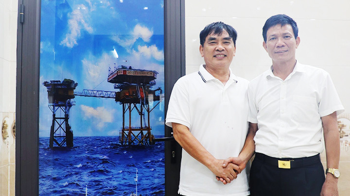 CĐĐ Phạm Khắc Lượng (tác giả) và Trung tá Dương Văn Hoan (bên phải) cạnh hình ảnh nhà giàn in phun trên cửa. Ảnh: PHƯƠNG DUNG