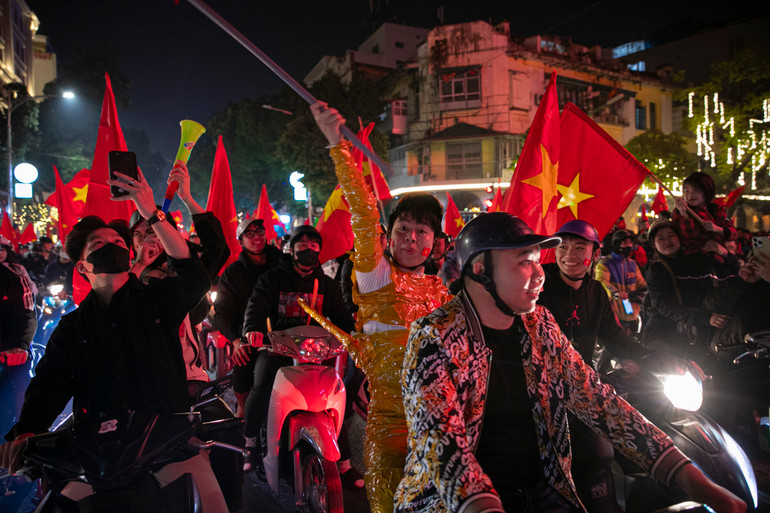 Dòng người mang theo cờ đỏ sao vàng tràn ra đường ăn mừng chiến thắng lịch sử của đội tuyển Việt Nam.