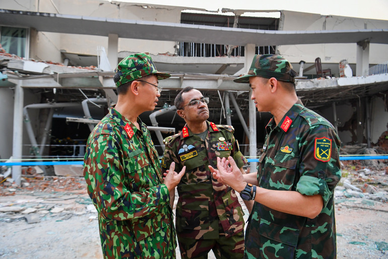 Trung tá Nguyễn Thắng Anh (bên phải) trao đổi với lực lượng cứu hộ Bangladesh tại hiện trường tìm kiếm, cứu nạn tại Naypyidaw.