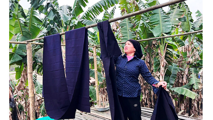 Chị Hoàng Thị Nơi phơi vải chàm chuẩn bị cho may áo mới để đến chợ tình hát Sli. Ảnh: TUẤN SƠN