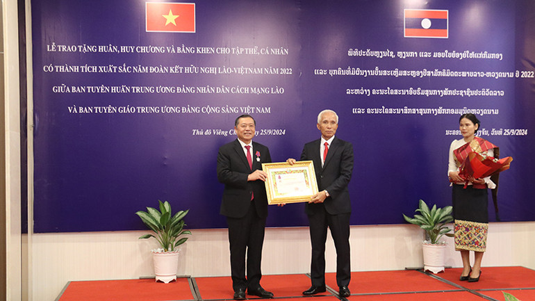 Bí thư Trung ương Đảng, Trưởng Ban Tuyên huấn Trung ương Đảng NDCM Lào thay mặt lãnh đạo Đảng, Nhà nước Lào trao tặng Huân chương Itxala hạng Ba cho Phó Bí thư Thường trực Ban Tuyên giáo Trung ương Đảng Cộng sản Việt Nam Lại Xuân Môn. (Ảnh: HẢI TIẾN)