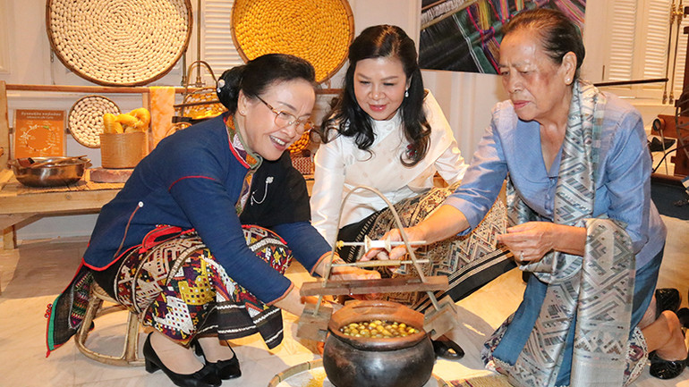 Phu nhân Ngô Phương Ly và Phu nhân Naly Sisoulith trải nghiệm kéo sợi tơ tằm tại Không gian trưng bày sản phẩm lụa truyền thống của Lào ở thủ đô Vientiane. (Ảnh: HẢI TIẾN)