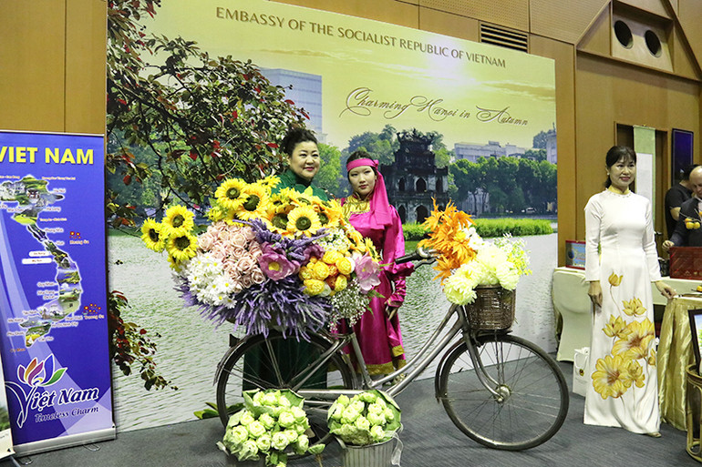 Bạn bè quốc tế chụp ảnh lưu niệm với những nét đặc trưng của mùa thu Hà Nội tại gian trưng bày của Đại sứ quán Việt Nam tại Lào. (Ảnh: HẢI TIẾN)