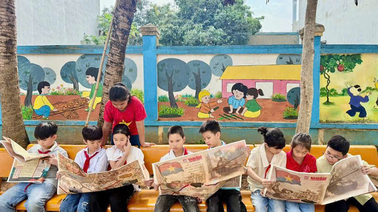 Các em học sinh Trường tiểu học và trung học cơ sở Thái Bình, thành phố Hòa Bình, chăm chú xem phụ san. (Ảnh: NGUYỄN TUẤN)