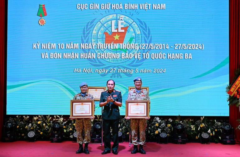 Thừa ủy quyền của Thủ tướng Chính phủ, Thượng tướng Phùng Sĩ Tấn trao Bằng khen của Thủ tướng Chính phủ tặng Bệnh viện dã chiến cấp 2, số 4 và Đại tá Mạc Đức Trọng, nguyên Đội trưởng Đội Công binh số 1, Cục Gìn giữ hòa bình Việt Nam.