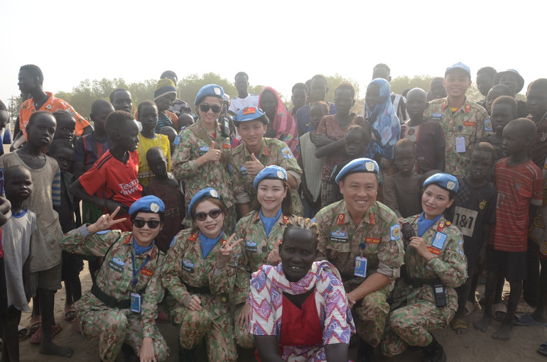 Các bác sĩ "mũ nồi xanh" Bệnh viện dã chiến cấp 2, số 5 của Việt Nam chụp ảnh cùng người dân tại Bentiu, bang Unity, Nam Sudan, tham dự Lễ mít-tinh kết hợp tuần hành, do Liên hợp quốc tổ chức, nhân Ngày Quốc tế Phụ nữ 8/3. Ảnh: Bệnh viện dã chiến cấp 2, số 5 cung cấp.