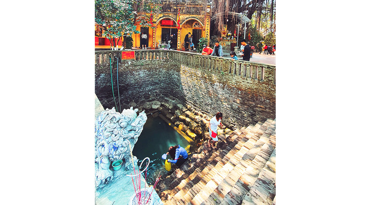 Du khách lấy nước từ giếng Ngọc trong khu di tích làng Diềm.