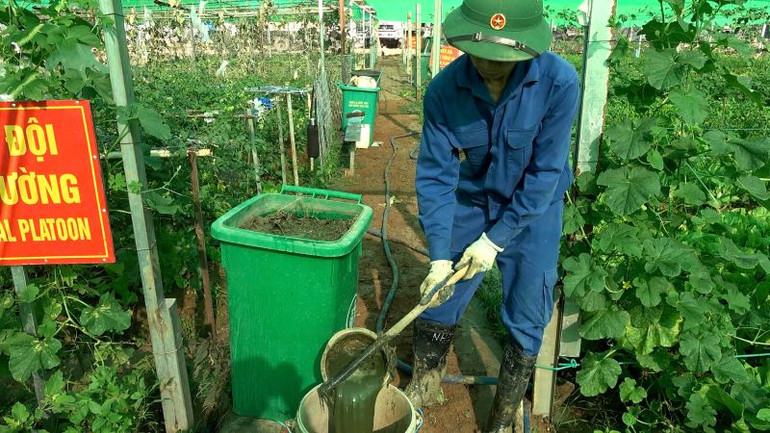 Cán bộ, nhân viên Đội Công binh số 3 cải tạo đất bằng cách gom nhặt cỏ cây chặt nhỏ và ngâm ủ, tận dụng rác thải hữu cơ từ bếp ăn làm phân xanh để tăng độ màu mỡ. Ảnh: Đội Công binh số 3 cung cấp.