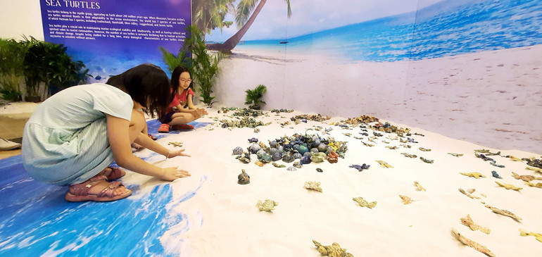 Trẻ em trải nghiệm với không gian trưng bày rùa gốm tại triển lãm.