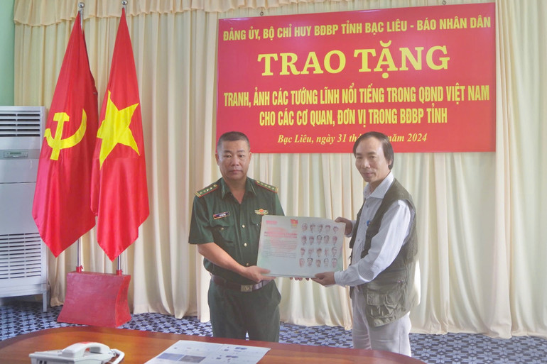 Đại tá Hà Văn Sao (bên trái) , Chủ nhiệm Chính trị Bộ đội Biên phòng tỉnh Bạc Liêu nhận bộ tranh các vị tướng tài danh do Văn phòng đại diện Báo Nhân Dân tại Bạc Liêu trao tặng
