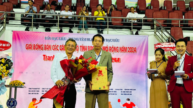 Tổng Biên tập báo Bạc Liêu Hàn Ái Tiến trao tặng hoa và cảm ơn đồng chí Nguyễn Minh Chánh (người cầm hoa), nguyên Tổng Biên tập báo Bạc Liêu và Chủ tịch Hội Nhà báo tỉnh Bạc Liêu. (Ảnh: TRỌNG DUY)