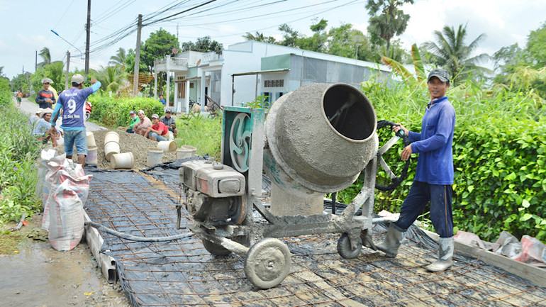 Bà con Khmer ở ấp Cái Giá, xã Hưng Hội (Vĩnh Lợi) tích cực đóng góp sức người và của cùng chính quyền địa phương làm đường bê-tông nối liền các ấp vùng sâu. (Ảnh: TRỌNG DUY)