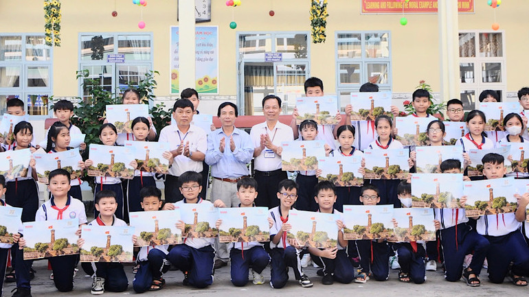 Thầy giáo Trần Văn Sơn, Bí thư Chi bộ, Hiệu trưởng Trường tiểu học Kim Đồng (thành phố Bạc Liêu) và Trưởng Văn phòng đại diện Báo Nhân Dân tại Bạc Liêu trao ấn phẩm đặc biệt phụ san Cột cờ Hà Nội cho các em học sinh.