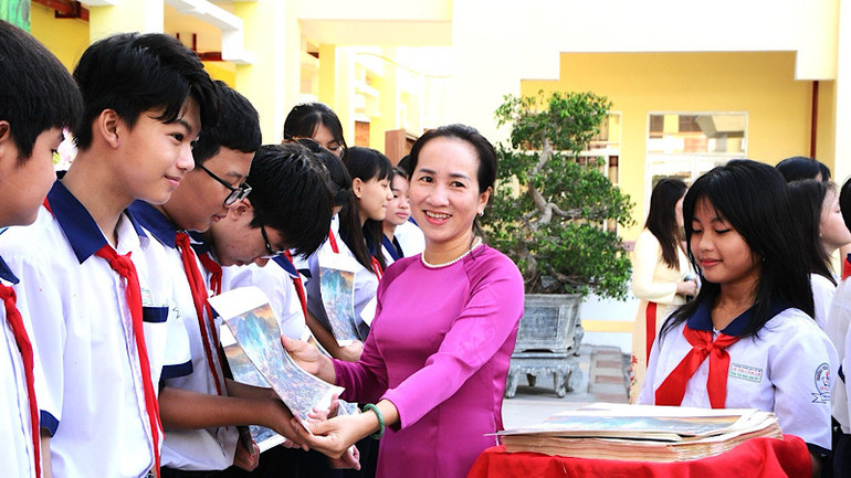 Cô Trần Kim Thi, Hiệu trưởng Trường trung học cơ sở Lê Thị Cẩm Lệ tặng tranh của Báo Nhân Dân cho những em học sinh xuất sắc.