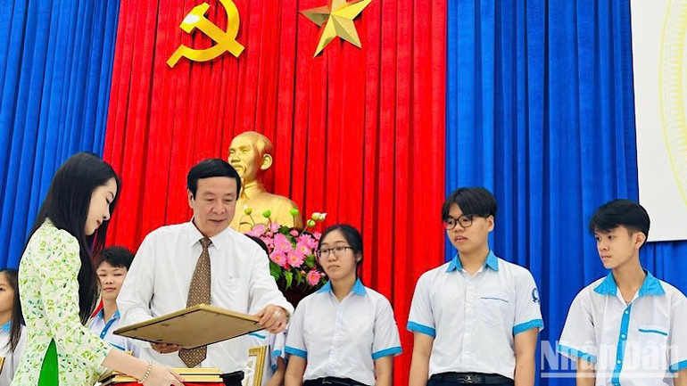 Thầy giáo Nguyễn Văn Bình, Trưởng phòng Giáo dục và Đào tạo thị xã Giá Rai (Bạc Liêu) tặng giấy khen và quà những học sinh khó khăn, học giỏi. (Ảnh: TRỌNG DUY)