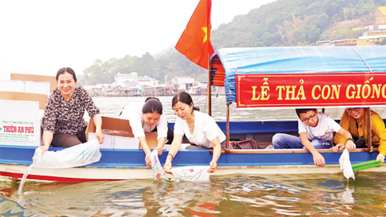 Đại diện ngành chức năng, doanh nghiệp thả con giống tôm, cua, cá xuống đầm Đông Hồ.