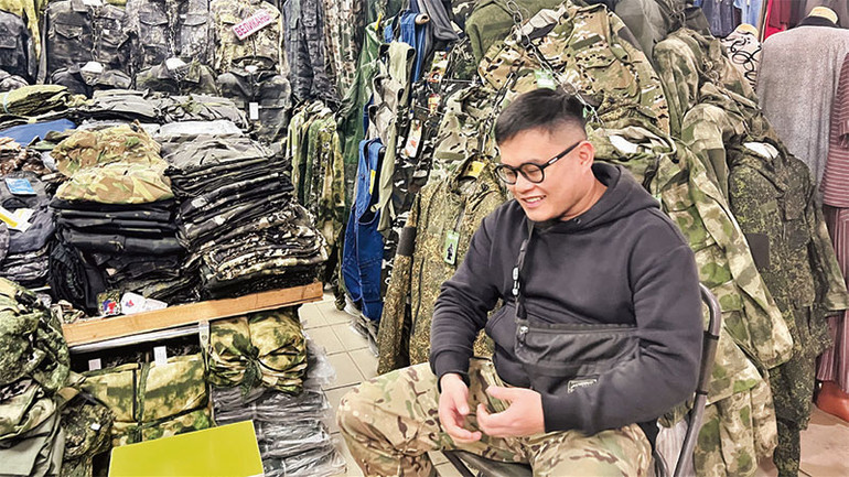 Thành ngồi trước gian hàng của mình trong chợ.