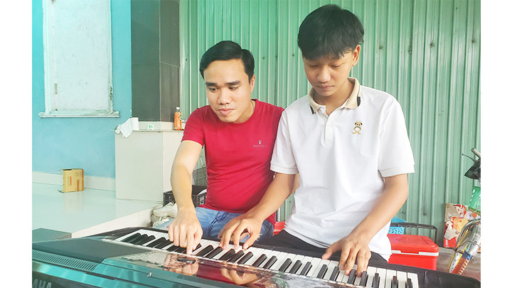 Anh Phước hướng dẫn cho một em học sinh nghèo Đức Phổ (Quảng Ngãi) các kỹ năng chơi đàn organ.