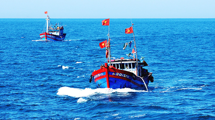 Thuyền đánh cá của ngư dân với lá cờ đỏ sao vàng tung bay trước gió.