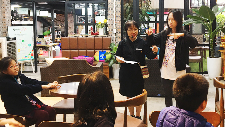 Chị Đính cùng nhân viên khuyết tật Ngô Phương Thảo đang diễn giải bằng tay với các em học sinh.