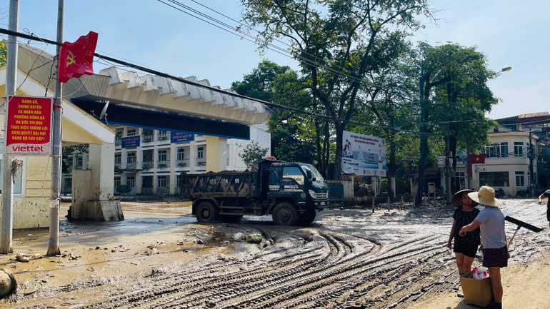 Các lực lượng khẩn trương hót dọn bùn đất tại sân trường trung học phổ thông Lý Thường Kiệt. (Ảnh: THANH SƠN)