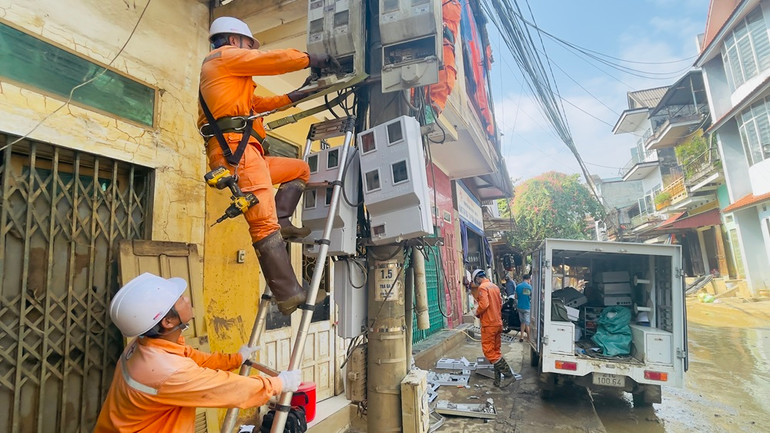 Công nhân điện lực thành phố Yên Bái lắp đặt công tơ trên trục đường Thanh Niên sau bão lũ. (Ảnh: THANH SƠN)