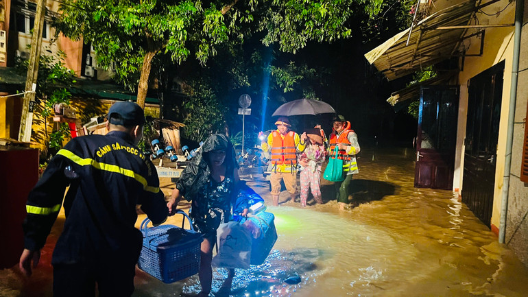 Đưa phụ nữ có con nhỏ ra khỏi vùng nguy hiểm.(Ảnh: THANH SƠN)