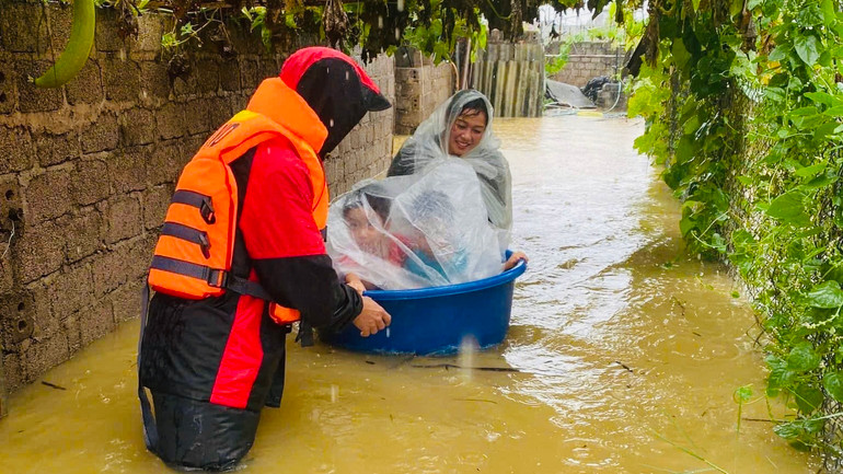 Đưa trẻ em ra khỏi vùng lũ.(Ảnh: THANH SƠN)
