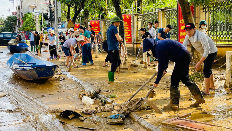 Dân quân cùng người dân dọn vệ sinh tại đường Hoàng Hoa Thám, nhằm sớm đưa cuộc sống trở lại bình thường. (Ảnh: THANH SƠN)