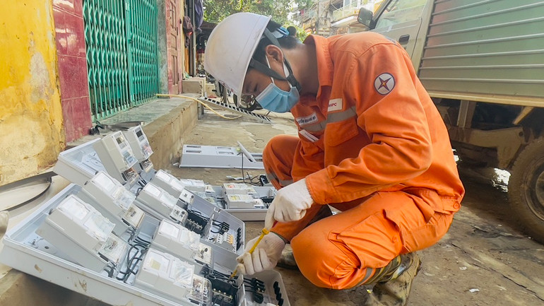 Nhân viên điện lực thành phố Yên Bái lắp đặt công tơ mới cho người dân bị thiệt hại. (Ảnh: THANH SƠN)