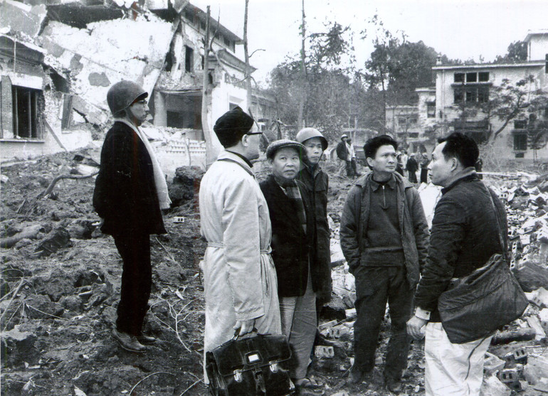 Trên đống đổ nát của Bệnh viện Bạch Mai, từ phải sang: nhà báo, nhà văn Thép Mới, nhà thơ Chế Lan Viên, nhà thơ Huy Cận (quàng khăn kẻ). Ngoài cùng bên trái là nhà văn Nguyễn Tuân. Mọi người đang nghe Anh hùng Lao động, GS, bác sĩ Trần Hữu Tước (người xách cặp) tố cáo tội ác của đế quốc Mỹ.