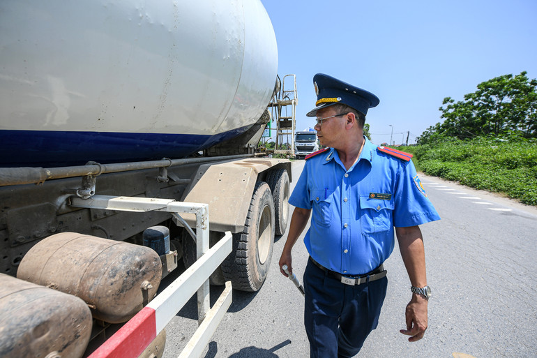 Ông Nguyễn Đức Thắng, cán bộ đội Thanh tra giao thông kiểm tra xe có dấu hiệu vi phạm chạy trên đê Hồng Vân. Nắng nóng giữa trưa cộng với nhiệt độ cao từ mặt đường càng khiến cho công việc trở nên khó khăn hơn.