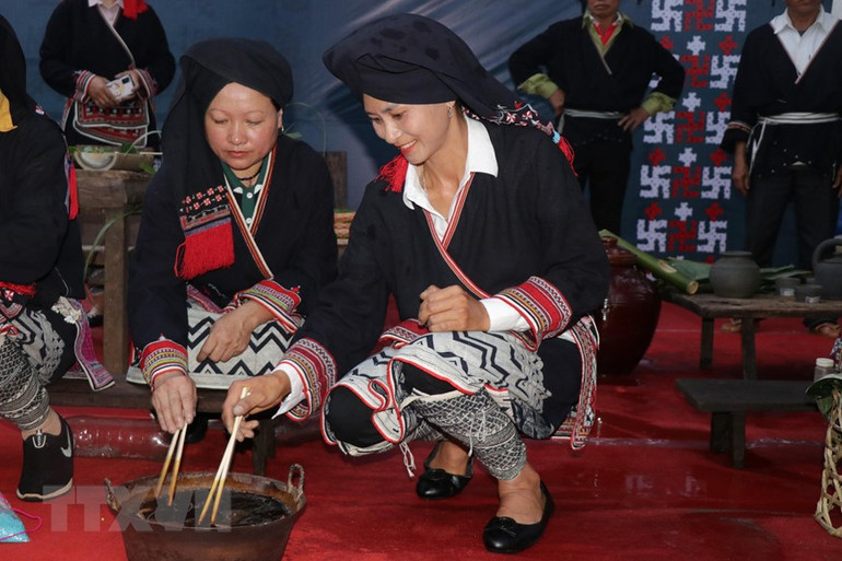 Nghệ nhân người Dao trình diễn nhuộm vải bằng nước chàm. (Ảnh: Hữu Quyết/TTXVN)