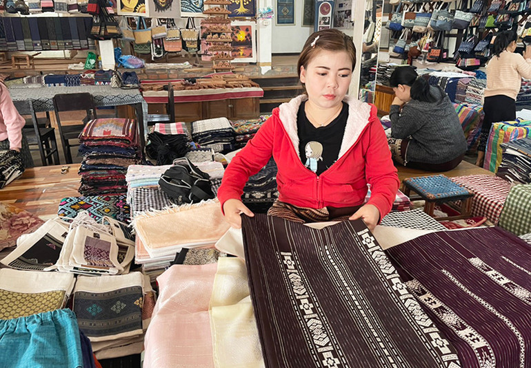 Giới thiệu sản phẩm vải dệt thủ công của Lào cho du khách. (Ảnh: Hải Tiến)