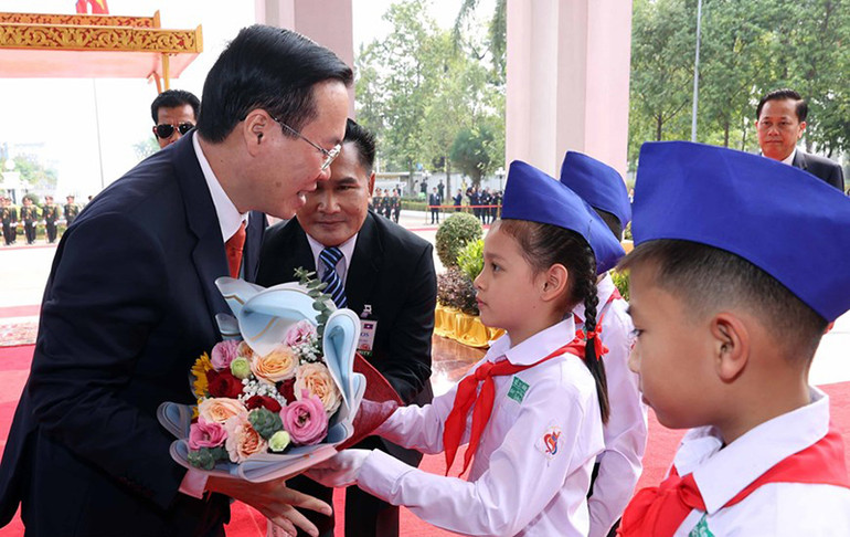 Thiếu nhi thủ đô Vientiane tặng hoa Chủ tịch nước Võ Văn Thưởng tại lễ đón. (Ảnh: Thống Nhất/TTXVN)