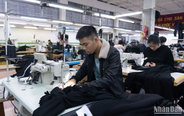 Đặng Thị Trang (áo đen ngồi sau) đang làm việc trong xưởng.