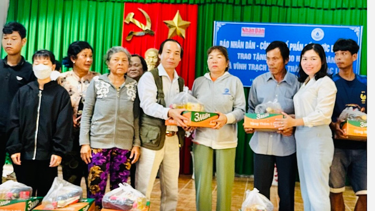Nhà báo Trọng Duy, đại diện Cơ quan Thường trực Báo Nhân Dân tại Cần Thơ và đồng chí Ngô Yến Nhiên, Bí thư Đảng ủy xã Vĩnh Trạch Đông trao quà các hộ nghèo của xã.