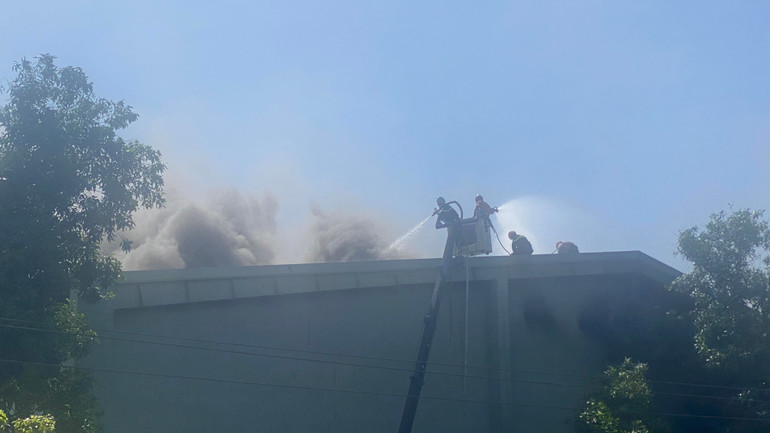 Lực lượng Cảnh sát Phòng cháy chữa cháy leo lên mái nhà kho nỗ lực dập lửa.