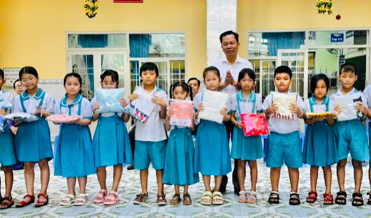 Thầy giáo Trần Văn Sơn, Bí thư Chi bộ, Hiệu trưởng Trường tiểu học Kim Đồng (thành phố Bạc Liêu) trao quà Tết cho các em học sinh hoàn cảnh khó khăn.