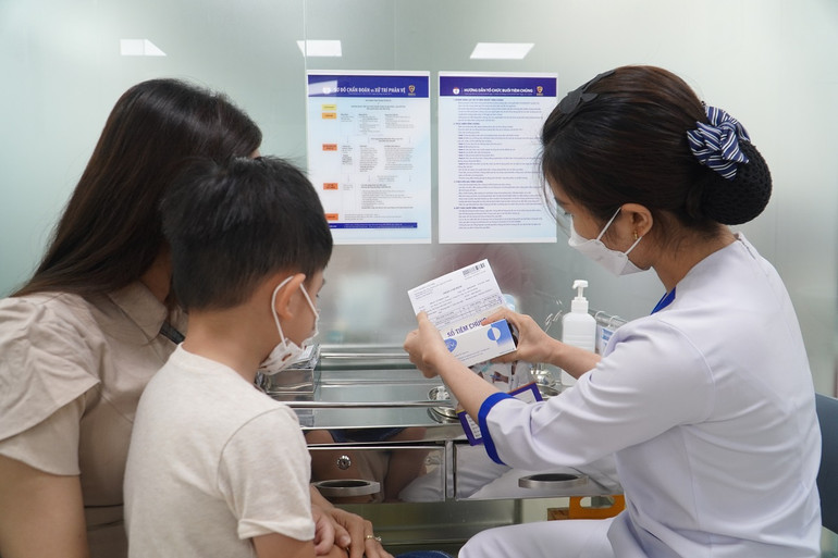 Nhân viên tiêm chủng rà soát lại thông tin người tiêm, loại vaccine, hạn sử dụng cho mẹ của trẻ.