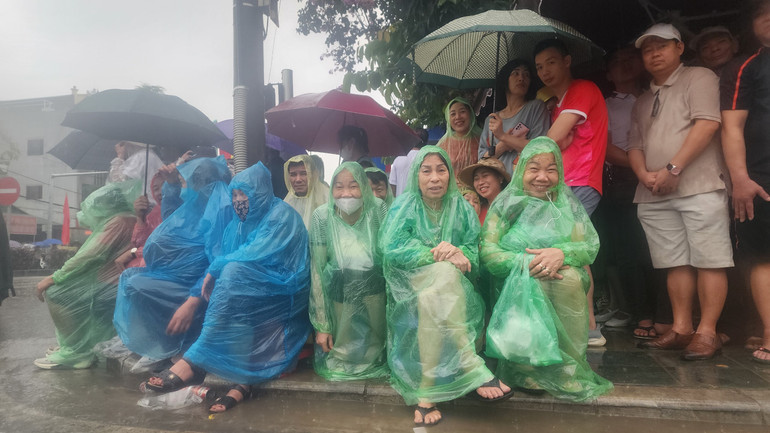 Bà con mặc áo mưa chờ xem lễ diễu binh.