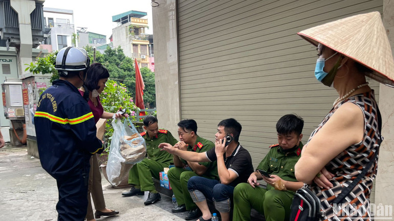 Người dân khu phố tiếp đồ ăn, nước uống cho các lực lượng làm việc tại hiện trường.