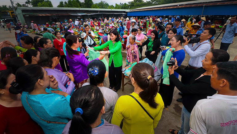 Phó Chủ tịch UBND tỉnh Hậu Giang (áo xanh) tặng áo bà ba cho các tiểu thương chợ nông thôn Vị Thanh.