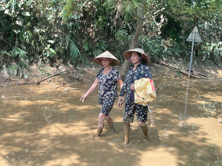 Bà con vượt sình lầy đến nhận quà cứu trợ của các mạnh thường quân.