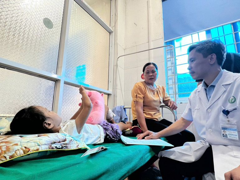 Phó Giáo sư, Tiến sĩ Nguyễn Mạnh Khánh thăm hỏi em bé là nạn nhân trong vụ sạt lở đất. Em đang được bà ngoại chăm sóc tại Bệnh viện đa khoa huyện Bảo Yên.