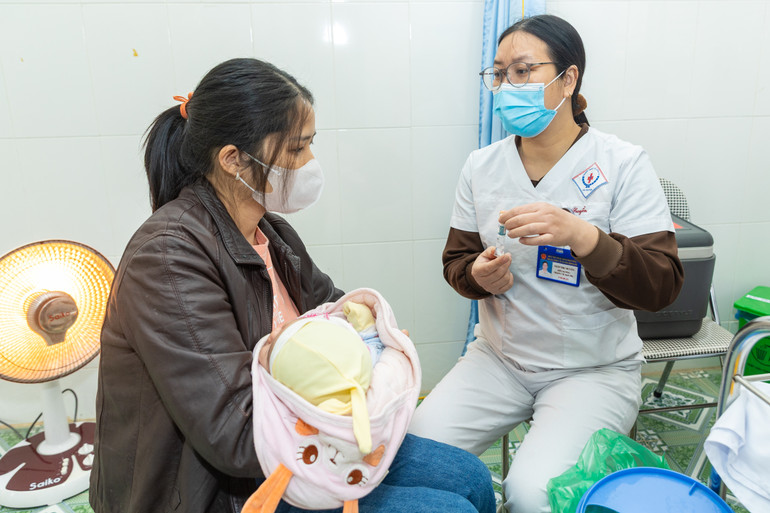 Nhân viên y tế giải thích cho chị Hữu về vaccine Rota cho con uống.
