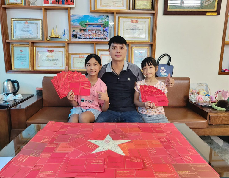 Nguyễn Văn Tỉnh cùng các con xếp hình lá cờ Tổ quốc từ những giấy chứng nhận hiến máu của mình.