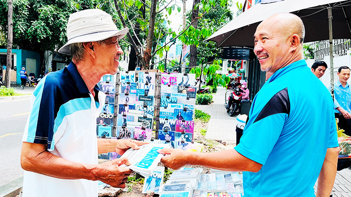 Ông Hùng (bên phải, áo xanh) vui vì còn nhiều khách quen ghé sạp mua báo mỗi ngày.