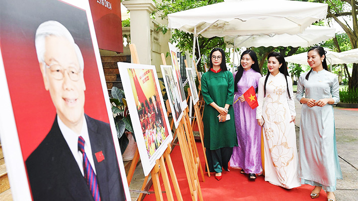 Nhiều bạn trẻ trong trang phục áo dài, cầm trên tay lá cờ Tổ quốc tham quan triển lãm.